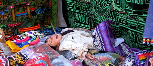A child plays among her mother's wares in the Sacred Valley of Peru